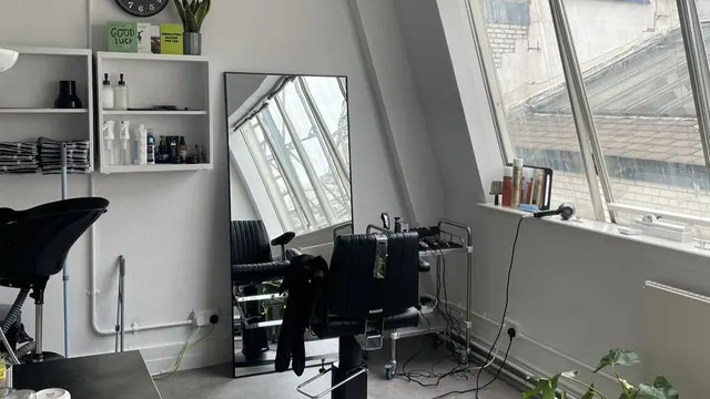The studio: a barber chair by a tall mirror and window